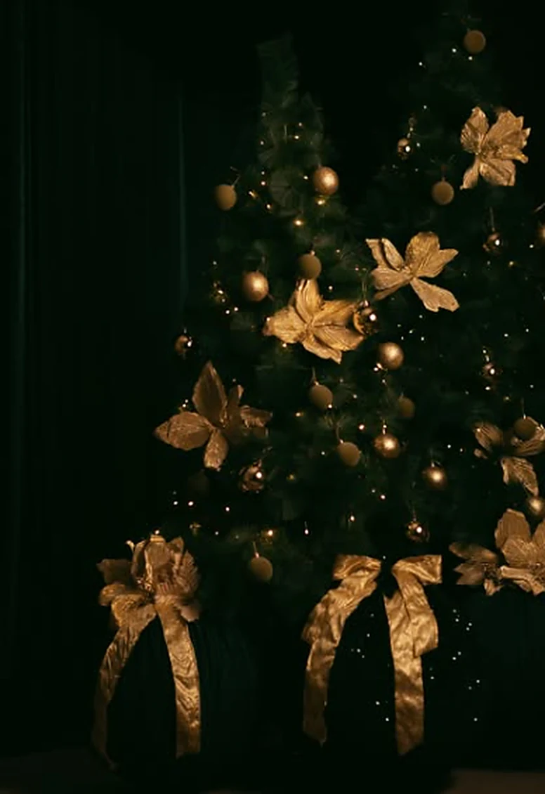Árvore de Natal em ambiente escuro com ornamentos dourados e luzes pontuais